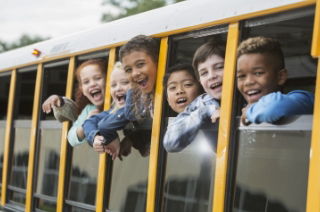 little kids smiling out the bus window