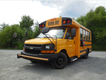 Yellow school bus parked in front of trees