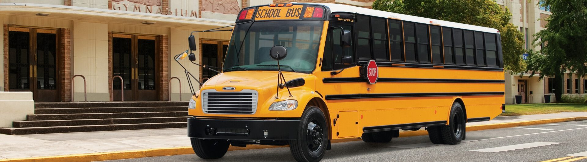 Yellow school bus parked in front of school gymnasium