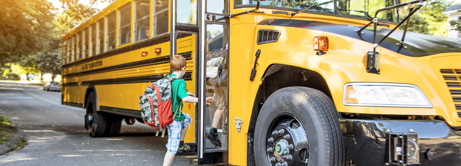 Little boy with green shirt getting on school bus