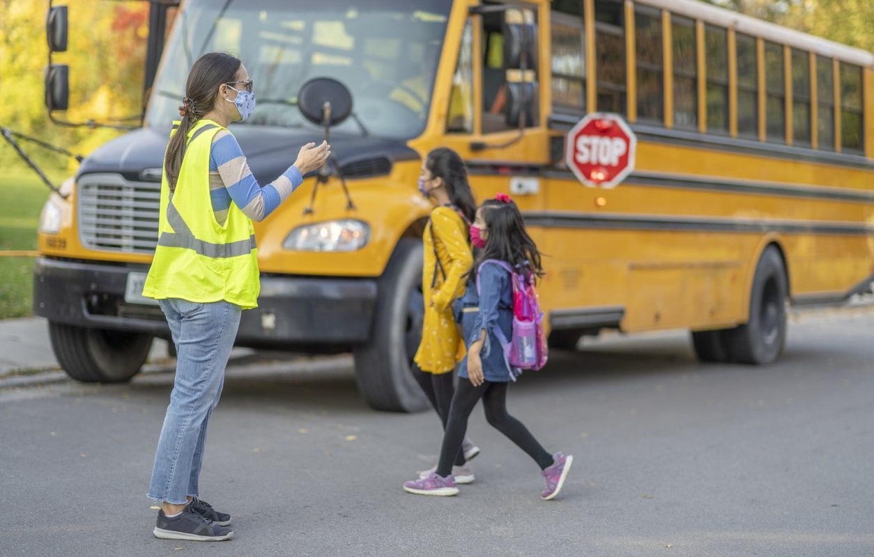 crossing guard helping two girls cross the street