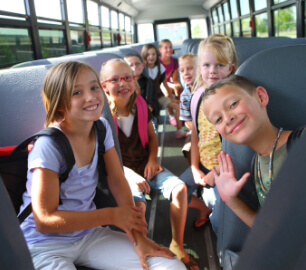 Little kids smiling as they sit on the bus