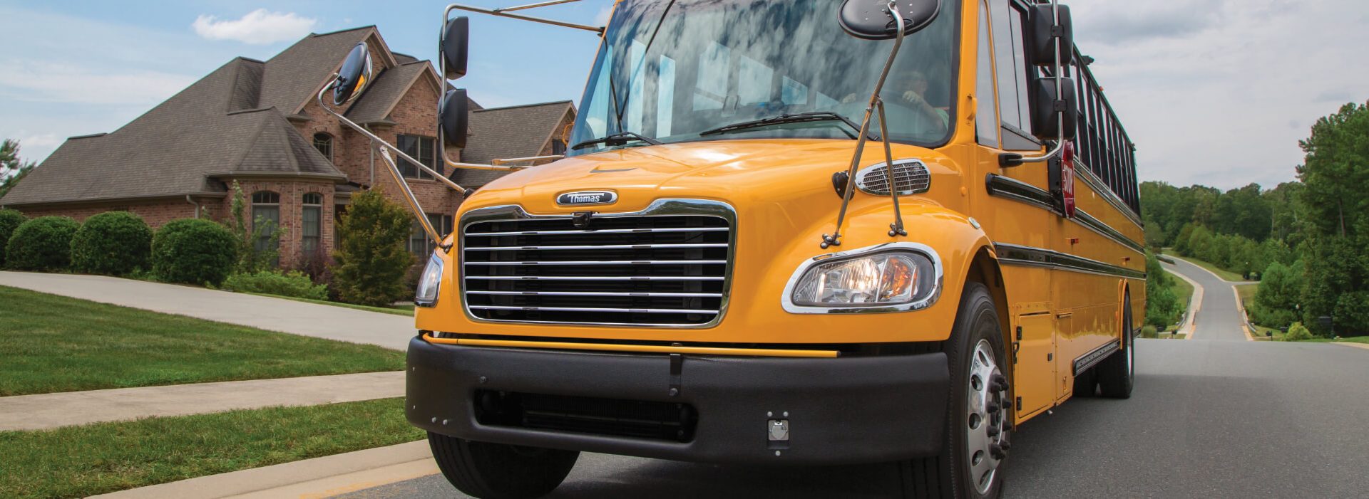 Yellow school bus driving through neighborhood