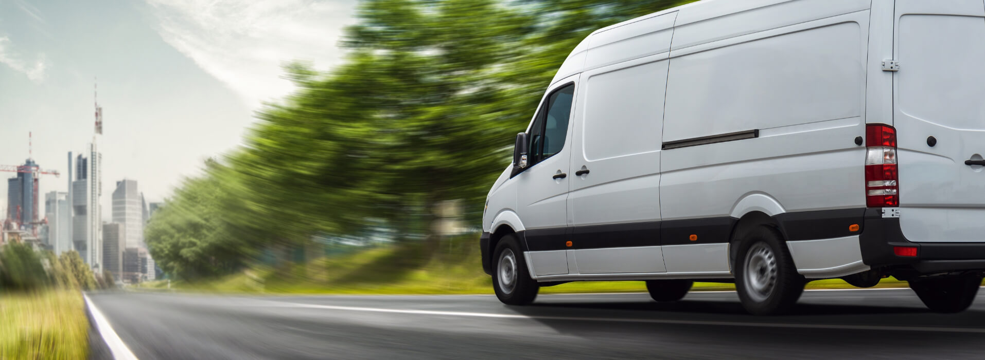 White van driving down road into city