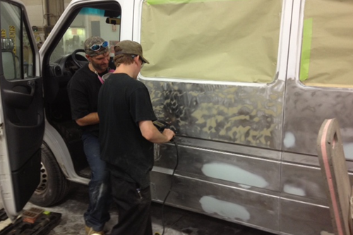 two technicians doing body work on old van