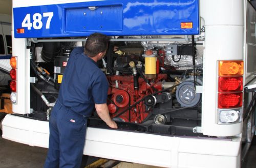 Man working on bus engine in the back of bus