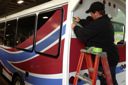 graphics installer installing vinyl on bus