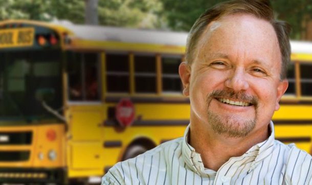 Man smiling in front of school bus