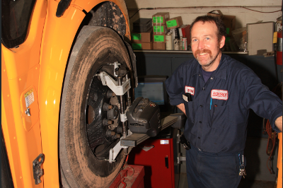 Technician smiling next to man working on bus