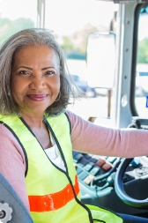 Woman with yellow safety vest in driver's seat of bus