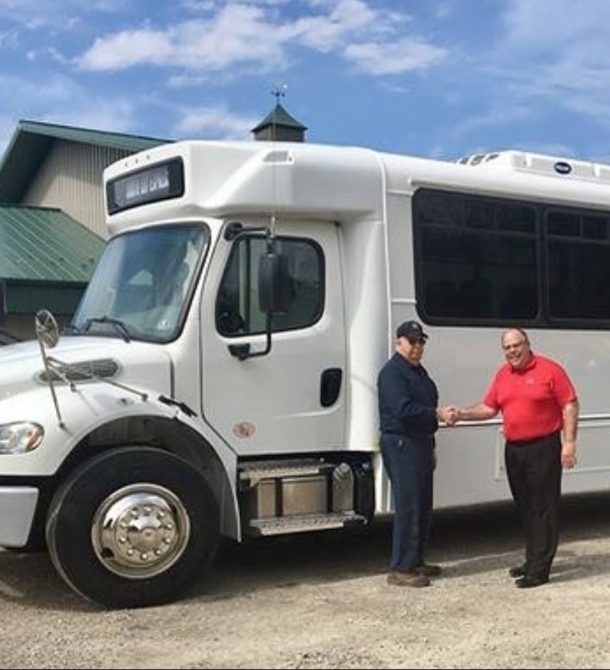 two men shaking hands in front of white bus