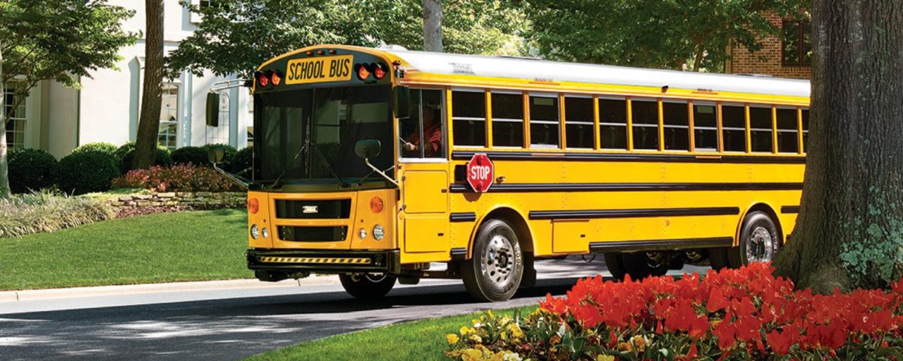 yellow school bus driving through neighborhood